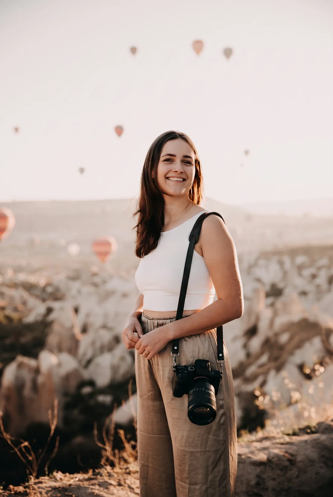 Jule Schnakenberg, founder of mazemade, smiling with her camera at sunrise among hot air balloons in Cappadocia